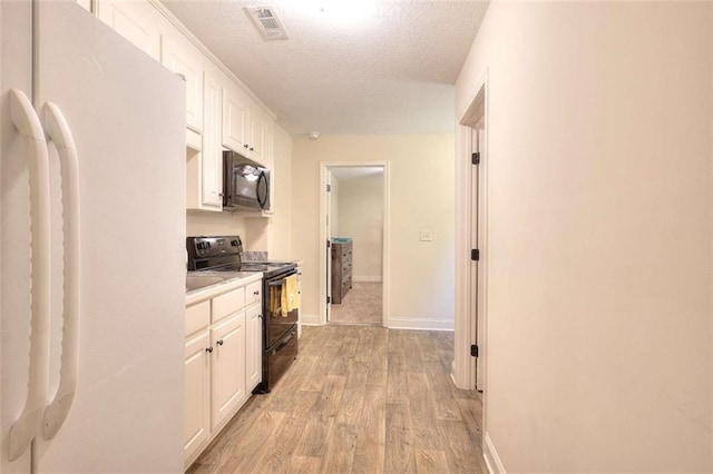 340 Thoroughbred Trl, Monroe, GA 30655 - kitchen with black appliances, a textured ceiling, white cabinetry, light wood-type flooring, and light countertops