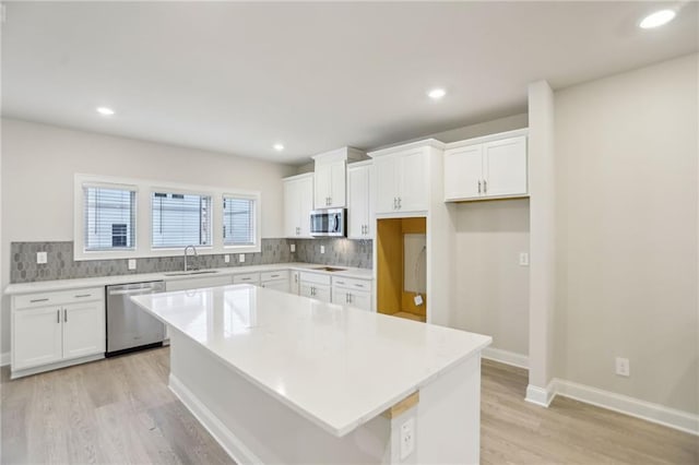 kitchen featuring stainless steel appliances, a center island, sink, and white cabinets