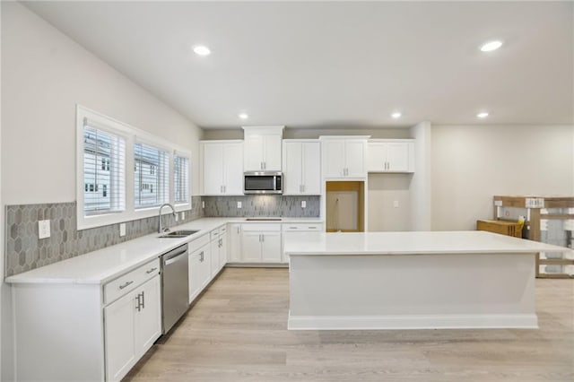 kitchen with sink, stainless steel appliances, a center island, and white cabinets