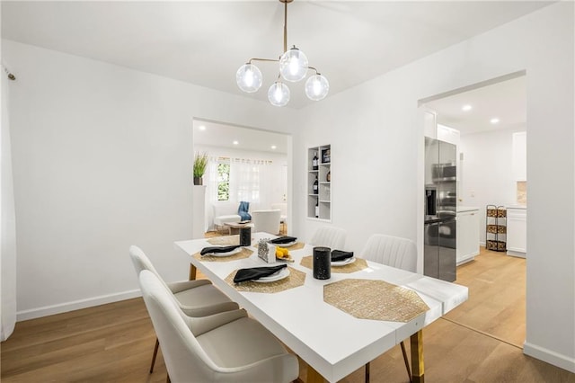 dining space featuring light wood-type flooring and an inviting chandelier