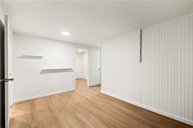 empty room featuring wood walls and light hardwood / wood-style flooring