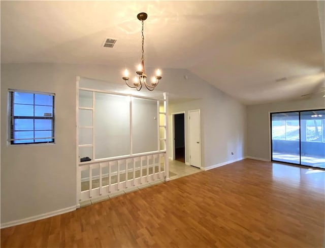 unfurnished room with a chandelier, hardwood / wood-style floors, and lofted ceiling