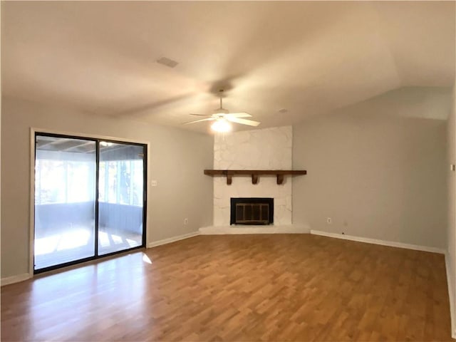 unfurnished living room with hardwood / wood-style flooring, ceiling fan, a stone fireplace, and vaulted ceiling