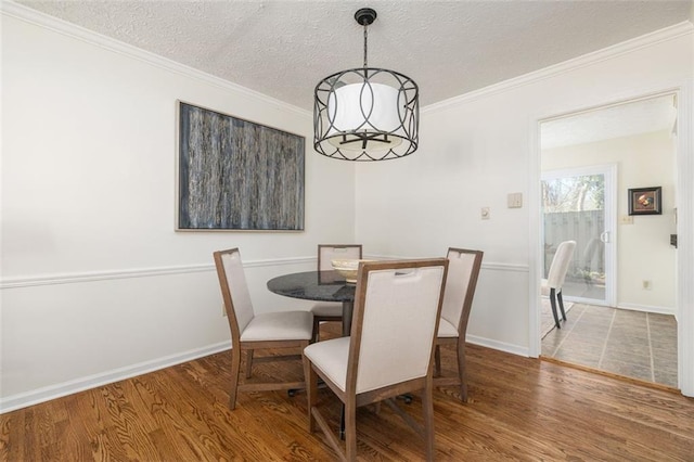 dining space with hardwood / wood-style flooring, a chandelier, crown molding, and a textured ceiling