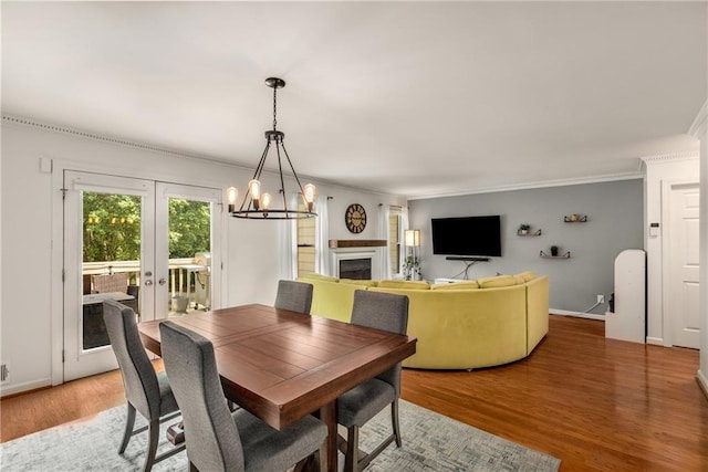 1341 Sheffield Glen Way NE, Atlanta, GA 30329 - dining space featuring crown molding, light wood-style flooring, a chandelier, a fireplace, and french doors