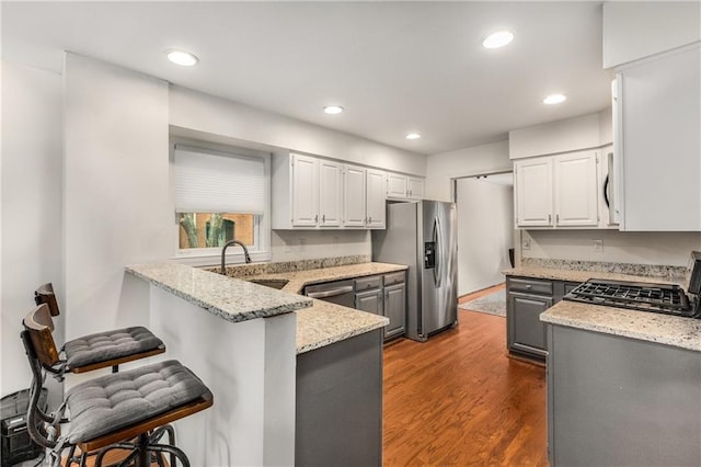 1341 Sheffield Glen Way NE, Atlanta, GA 30329 - kitchen featuring appliances with stainless steel finishes, a sink, light stone counters, a peninsula, and a kitchen bar