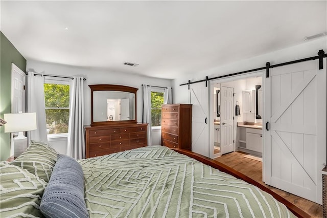 1341 Sheffield Glen Way NE, Atlanta, GA 30329 - bedroom with a barn door, multiple windows, wood finished floors, and connected bathroom