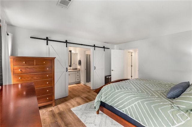 1341 Sheffield Glen Way NE, Atlanta, GA 30329 - bedroom featuring a barn door, wood finished floors, and ensuite bath