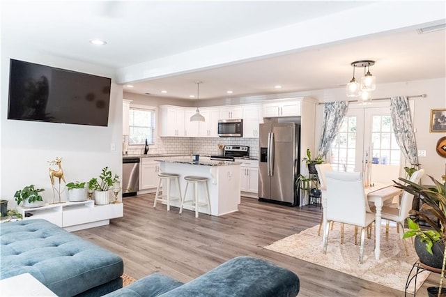 living room with light wood finished floors, recessed lighting, visible vents, and french doors