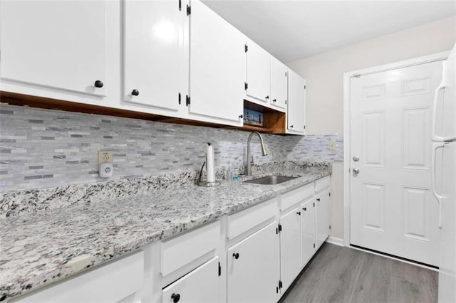 6671 Gano Dr, Riverdale, GA 30274 - kitchen with wood finished floors, white cabinets, tasteful backsplash, light stone counters, and white refrigerator
