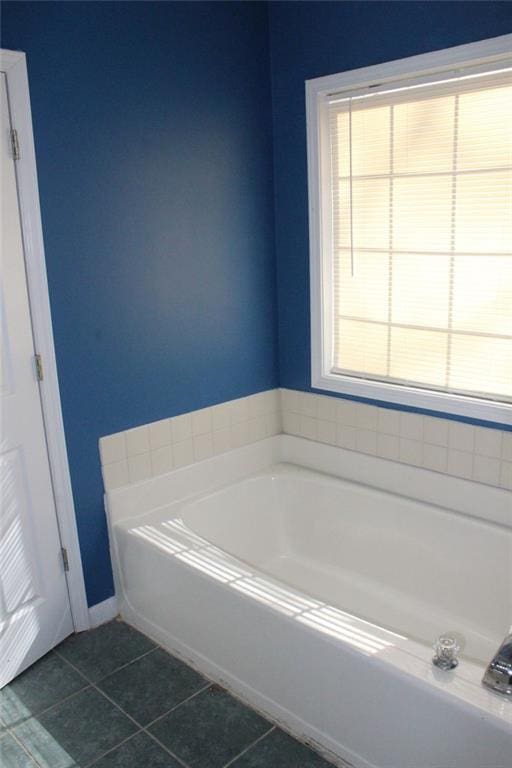 bathroom featuring tile patterned flooring, a washtub, and a wealth of natural light