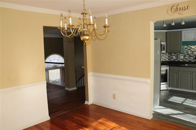 unfurnished dining area with ornamental molding, dark wood-type flooring, sink, and an inviting chandelier