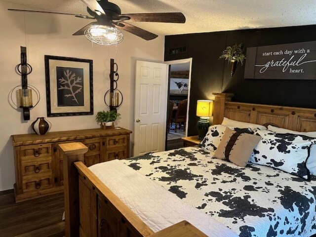 bedroom featuring ceiling fan, dark wood-style flooring, and a textured ceiling