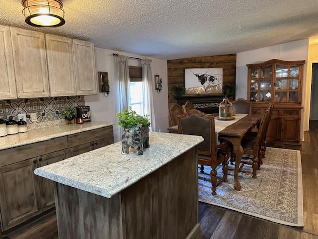 kitchen featuring a textured ceiling, a fireplace, dark wood-style flooring, and a kitchen island