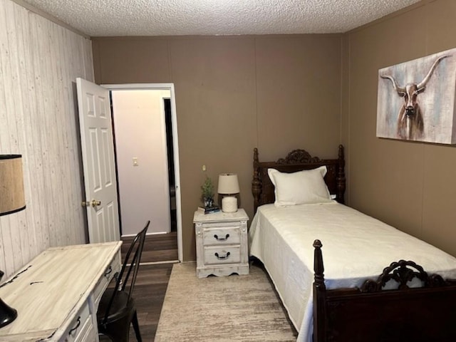 bedroom with wood finished floors, wood walls, and a textured ceiling