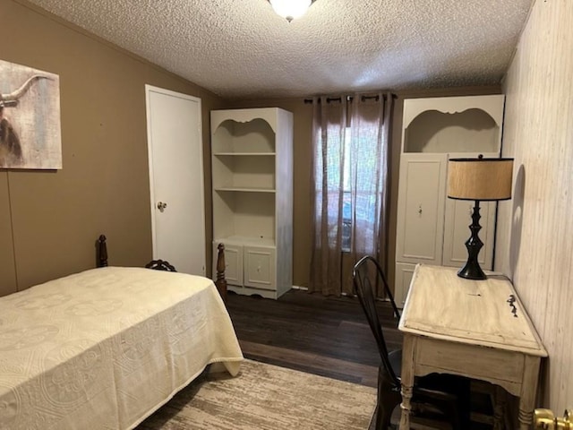 bedroom with vaulted ceiling, a textured ceiling, and dark wood-style flooring