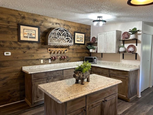 bar with stainless steel microwave, a textured ceiling, dark wood-type flooring, and wooden walls