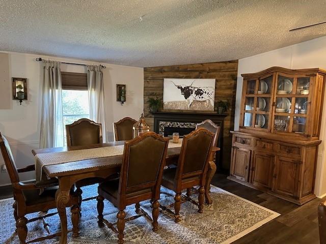 dining space with wooden walls, dark wood finished floors, a high end fireplace, and a textured ceiling