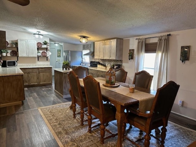 dining room with dark wood-style flooring, a wealth of natural light, and a textured ceiling