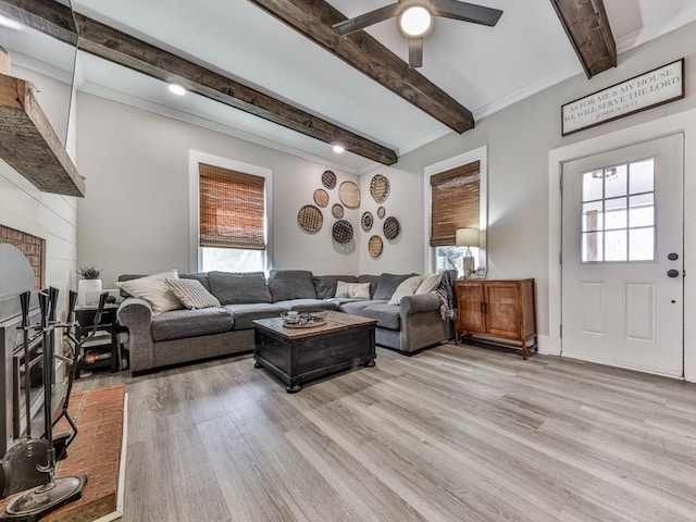 living room with light wood-style floors, a healthy amount of sunlight, beamed ceiling, and a fireplace