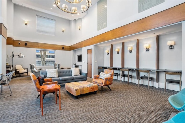 living room with a towering ceiling, a chandelier, and dark carpet