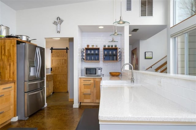 kitchen featuring backsplash, a barn door, visible vents, and appliances with stainless steel finishes