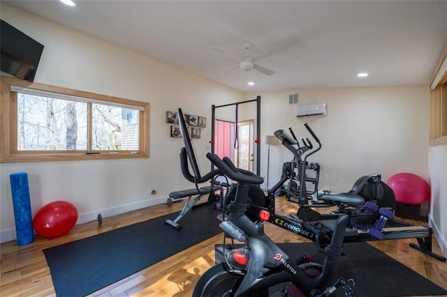 exercise area with wood finished floors, recessed lighting, ceiling fan, an AC wall unit, and baseboards