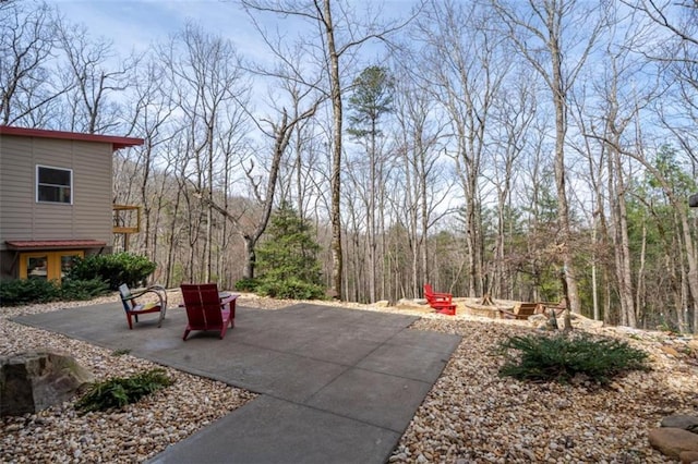 view of patio / terrace featuring a fire pit and a view of trees