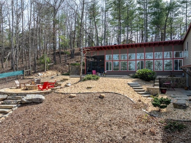 back of house with a fire pit, a sunroom, and a patio area