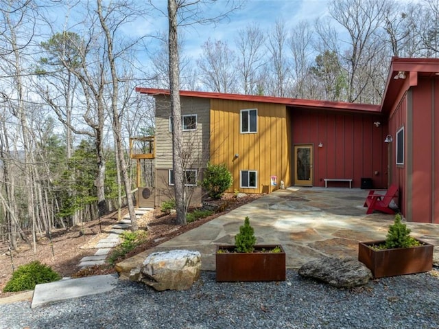 rear view of property with board and batten siding and a patio