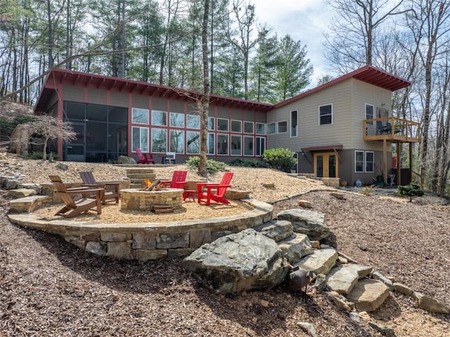 back of house with a sunroom, a patio, a fire pit, and french doors