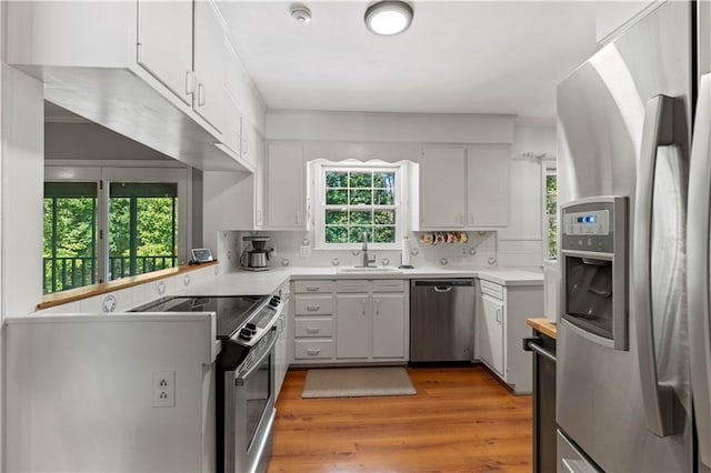 650 Crestview Ter, Gainesville, GA 30501 - kitchen with appliances with stainless steel finishes, light countertops, light wood-type flooring, white cabinetry, and decorative backsplash
