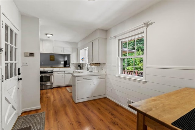 650 Crestview Ter, Gainesville, GA 30501 - kitchen with stainless steel stove, light countertops, light wood-style floors, white cabinetry, and a peninsula