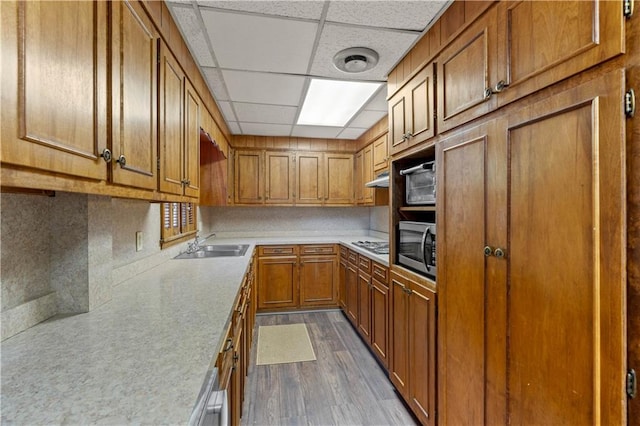 650 Crestview Ter, Gainesville, GA 30501 - kitchen featuring brown cabinetry, stainless steel microwave, light countertops, dark wood-style flooring, and a paneled ceiling