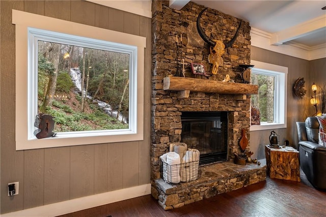 living room with beam ceiling, a stone fireplace, and hardwood / wood-style flooring