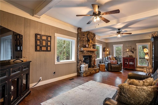 living area with dark wood-style floors, a stone fireplace, and beamed ceiling