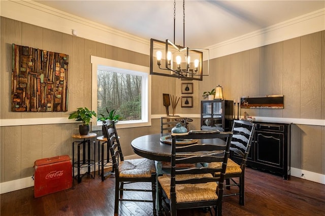 dining room featuring a notable chandelier, wooden walls, baseboards, and wood finished floors