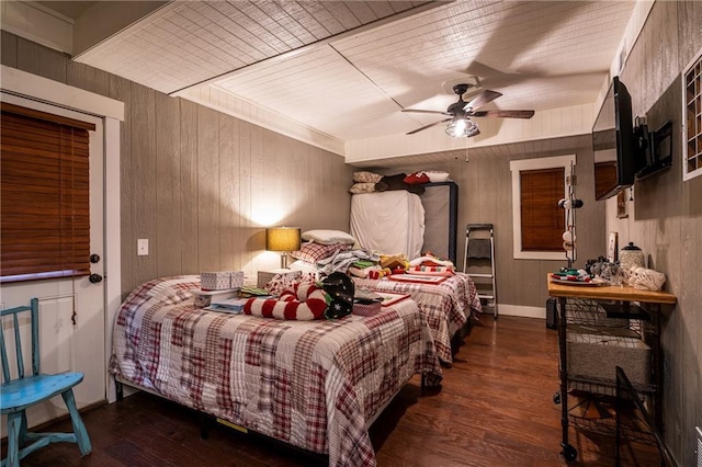 bedroom with ceiling fan, wooden walls, and wood finished floors