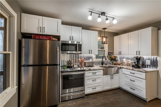 kitchen with light stone counters, dark wood-style flooring, stainless steel appliances, white cabinetry, and a sink