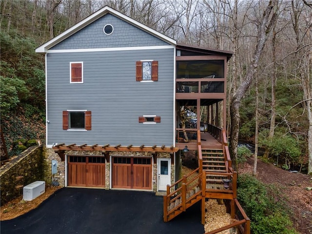 view of front of home with a garage, aphalt driveway, and stairway