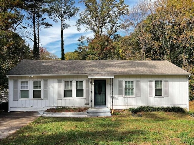 ranch-style home featuring board and batten siding, a front yard, and roof with shingles