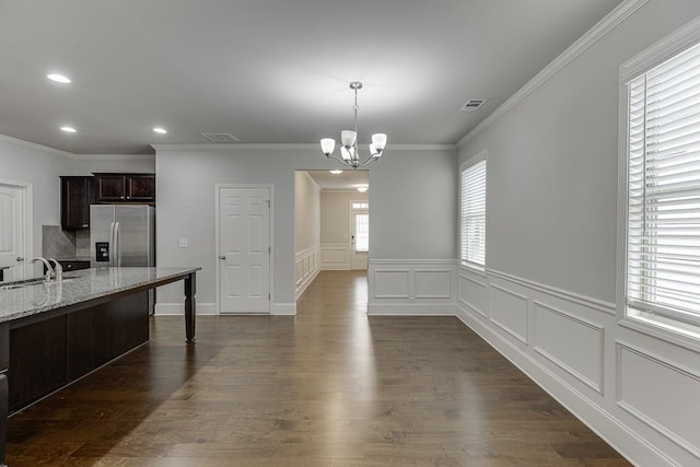 dining space featuring dark wood-style floors, visible vents, ornamental molding, and an inviting chandelier