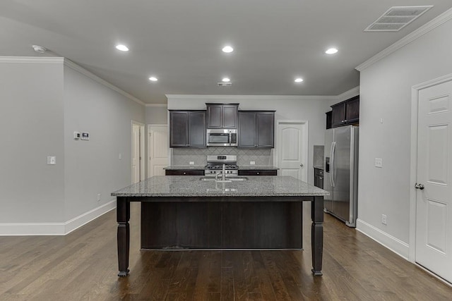 kitchen featuring stainless steel appliances, light stone counters, an island with sink, and visible vents