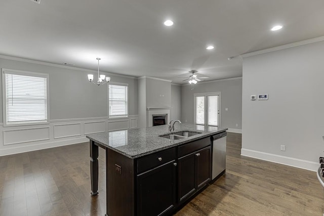 kitchen featuring dishwasher, ornamental molding, dark wood-type flooring, a fireplace, and a sink