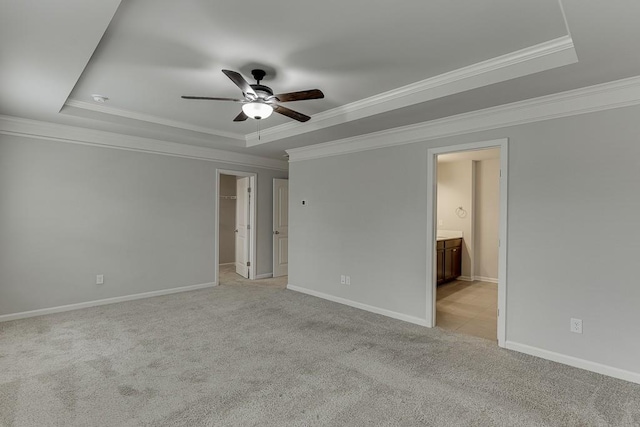 interior space featuring a ceiling fan, a tray ceiling, light carpet, and baseboards