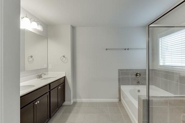 bathroom featuring a garden tub, double vanity, a sink, baseboards, and tile patterned floors