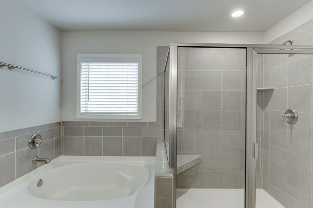 bathroom featuring a garden tub and a shower stall