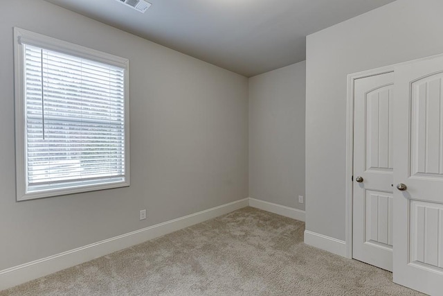 carpeted spare room featuring visible vents and baseboards