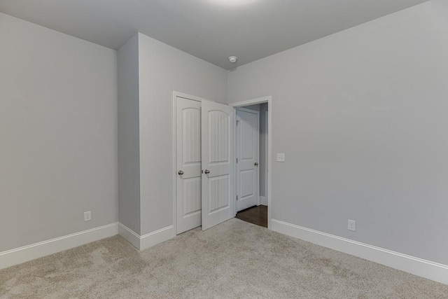 unfurnished bedroom with a closet, baseboards, and carpet flooring