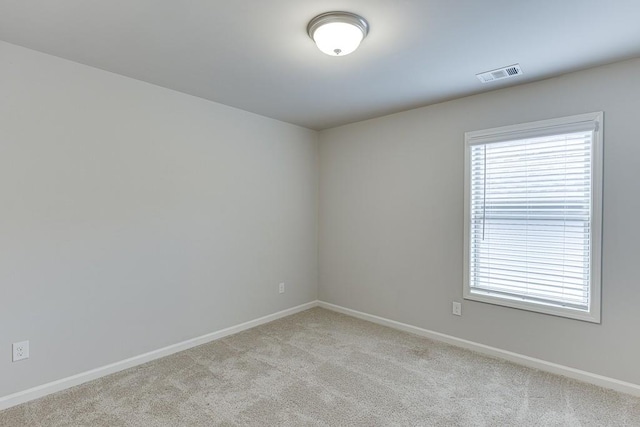 carpeted spare room featuring visible vents and baseboards